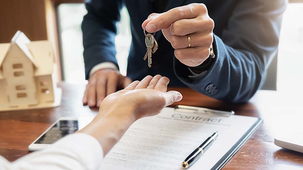 A person handing house keys over to another person